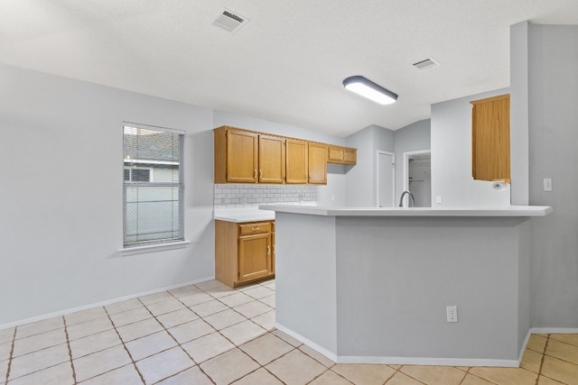 kitchen featuring vaulted ceiling, decorative backsplash, light tile patterned floors, and kitchen peninsula