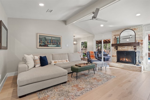 living room featuring light hardwood / wood-style floors, a stone fireplace, vaulted ceiling with beams, and ceiling fan