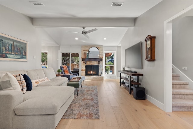 living room featuring light hardwood / wood-style floors, a stone fireplace, plenty of natural light, and ceiling fan