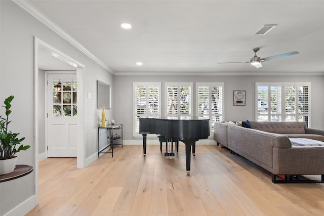 living room with light hardwood / wood-style floors, a healthy amount of sunlight, and crown molding