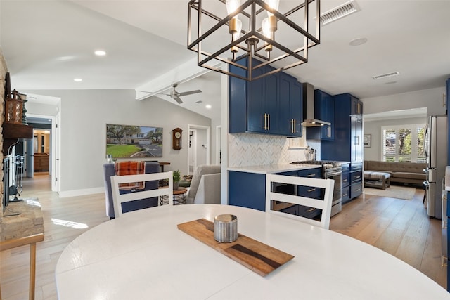 dining room with light hardwood / wood-style floors, lofted ceiling, and ceiling fan with notable chandelier