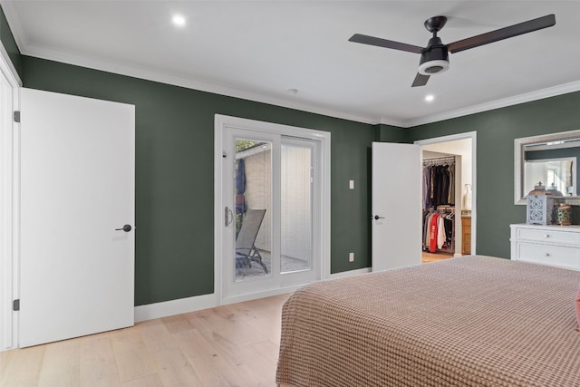 unfurnished bedroom featuring ceiling fan, ornamental molding, light wood-type flooring, and a walk in closet