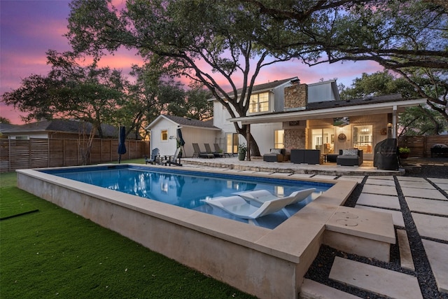 pool at dusk featuring a patio, a lawn, and outdoor lounge area