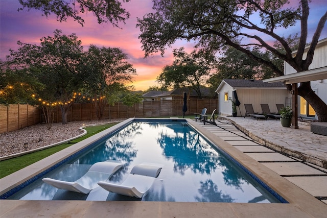 pool at dusk with a patio area