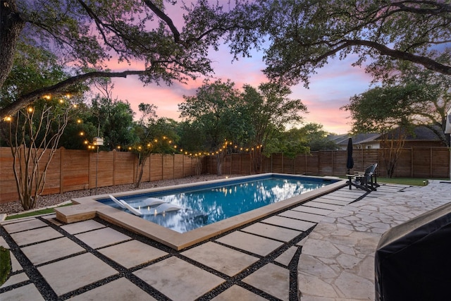 pool at dusk featuring a patio area