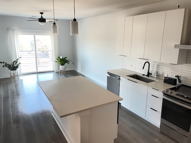 kitchen featuring sink, a center island, white cabinetry, stainless steel appliances, and decorative light fixtures