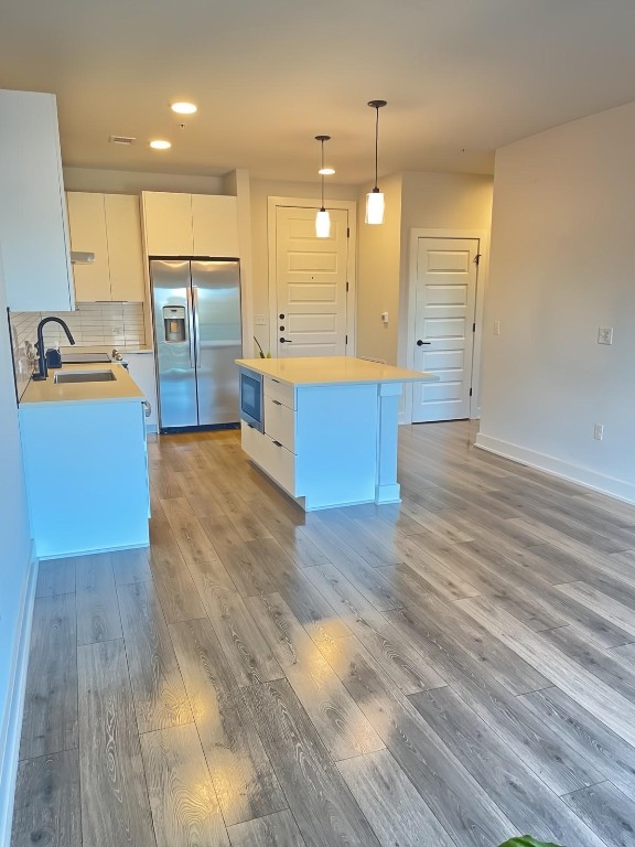 kitchen featuring white cabinets, a kitchen island, appliances with stainless steel finishes, light hardwood / wood-style flooring, and sink