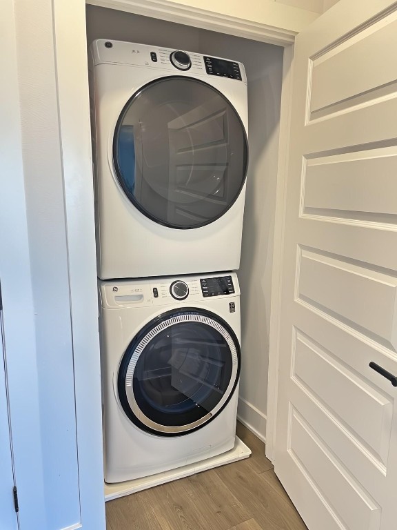 laundry area featuring dark hardwood / wood-style floors and stacked washer / drying machine