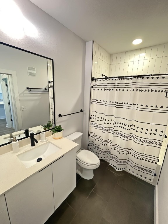 bathroom with vanity, walk in shower, toilet, and tile patterned flooring