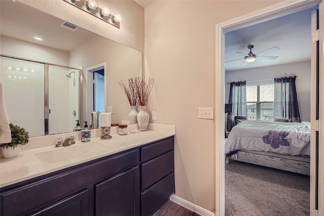 bathroom with a shower with door, vanity, and ceiling fan