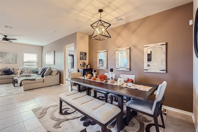 tiled dining space featuring ceiling fan with notable chandelier