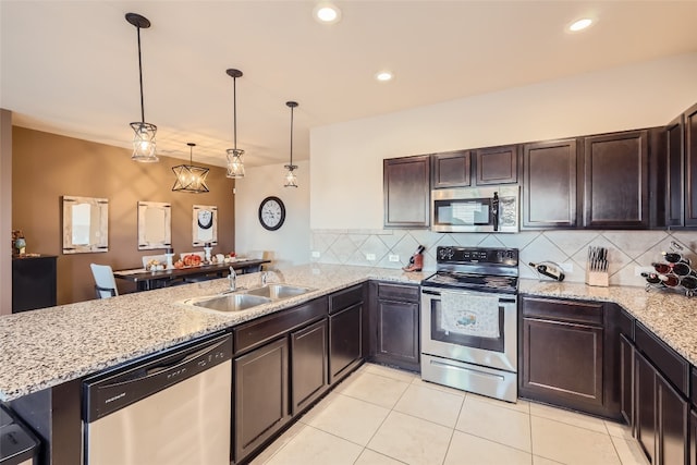 kitchen featuring tasteful backsplash, sink, kitchen peninsula, stainless steel appliances, and pendant lighting