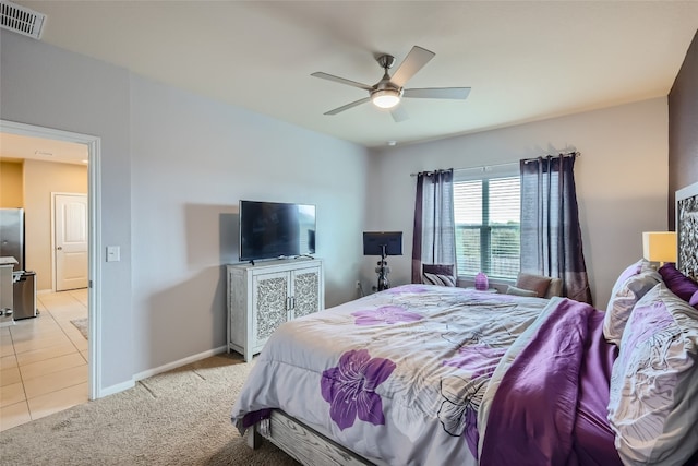 bedroom with ceiling fan, light tile patterned floors, and stainless steel fridge