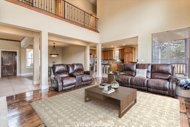 living room with light hardwood / wood-style flooring and a towering ceiling