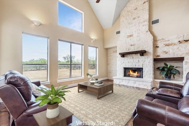 living room featuring a stone fireplace, high vaulted ceiling, and wood-type flooring