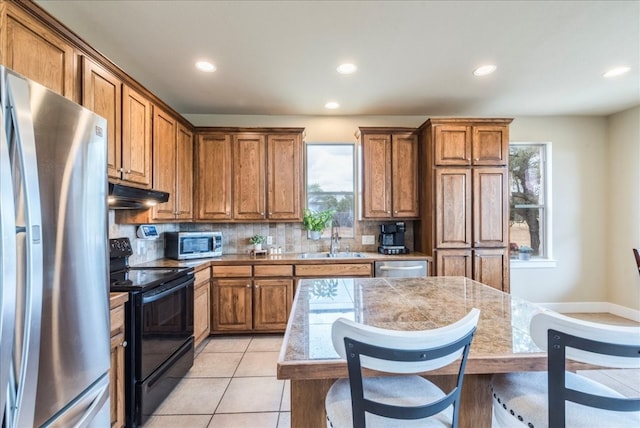 kitchen featuring a center island, sink, stainless steel appliances, decorative backsplash, and light tile patterned floors