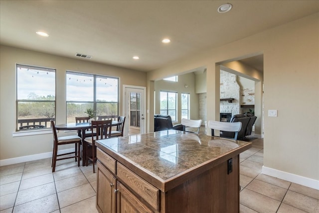 kitchen featuring a kitchen island, light tile patterned floors, and a fireplace