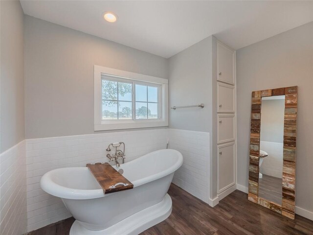 406 Blume Ln, Ledbetter, TX 78946 - bathroom with tile walls, a wainscoted wall, wood finished floors, and a soaking tub