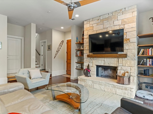 living room featuring a stone fireplace and wood-type flooring