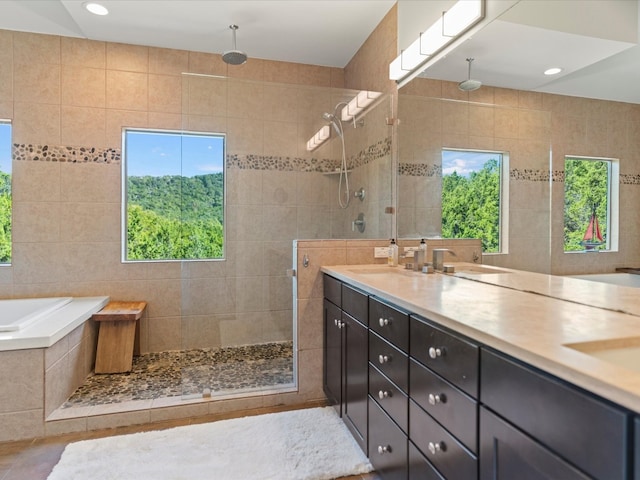 bathroom with vanity, independent shower and bath, tile patterned floors, and tile walls