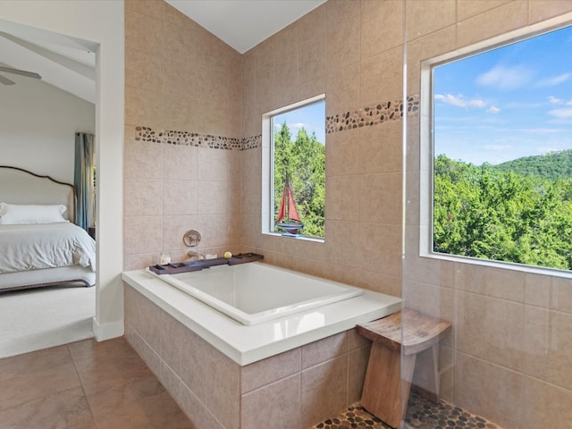 bathroom featuring tiled bath, plenty of natural light, and vaulted ceiling