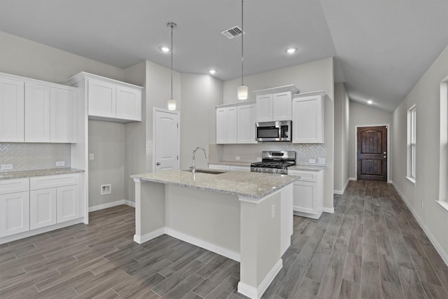 kitchen featuring light stone countertops, appliances with stainless steel finishes, sink, white cabinets, and hanging light fixtures