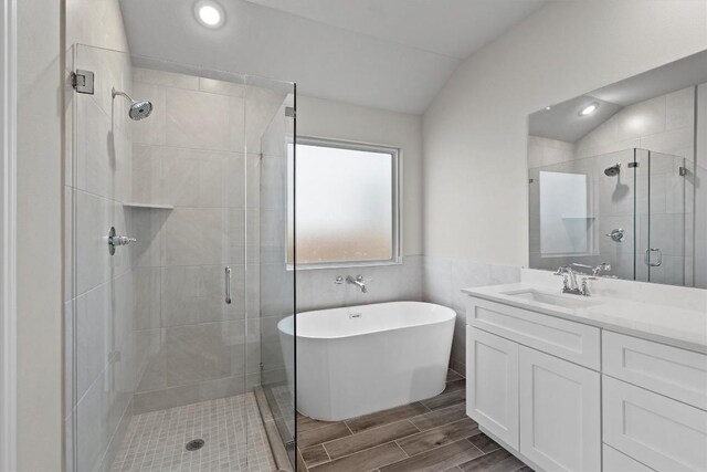 bathroom featuring vanity, independent shower and bath, and lofted ceiling