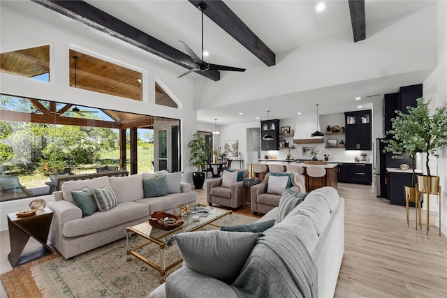 living room with ceiling fan, high vaulted ceiling, beamed ceiling, and light hardwood / wood-style flooring