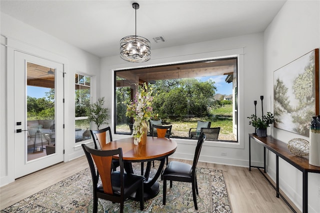 dining room with light hardwood / wood-style floors, an inviting chandelier, and plenty of natural light