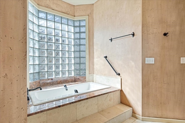 bathroom with tile patterned floors, tiled tub, and a wealth of natural light