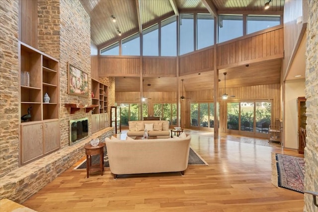 living room featuring ceiling fan, a healthy amount of sunlight, a fireplace, and high vaulted ceiling