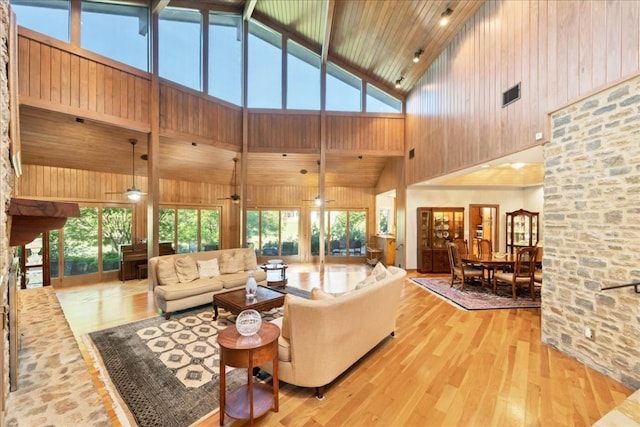 living room with light hardwood / wood-style floors, high vaulted ceiling, plenty of natural light, and ceiling fan