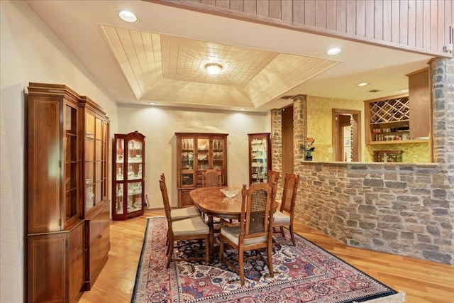 dining area featuring light hardwood / wood-style floors, bar, and a tray ceiling