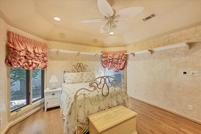 bedroom featuring ceiling fan, crown molding, and light hardwood / wood-style flooring