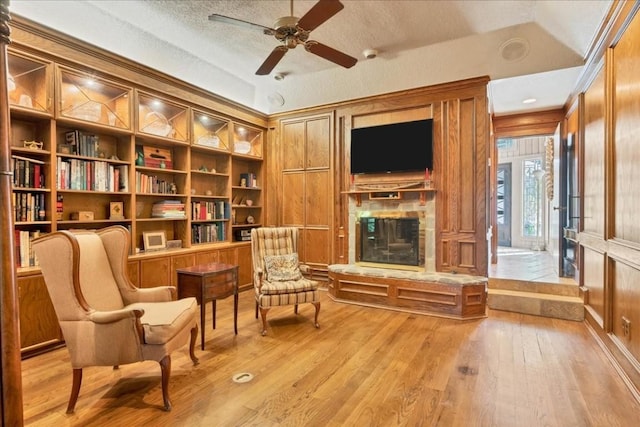 100 Silver Spur, Horseshoe Bay, TX 78657 - sitting room featuring light wood-style floors, a glass covered fireplace, ceiling fan, crown molding, and a decorative wall