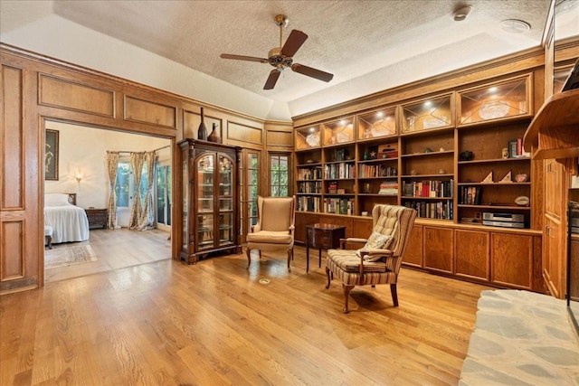 living area featuring ceiling fan, a textured ceiling, and light hardwood / wood-style flooring