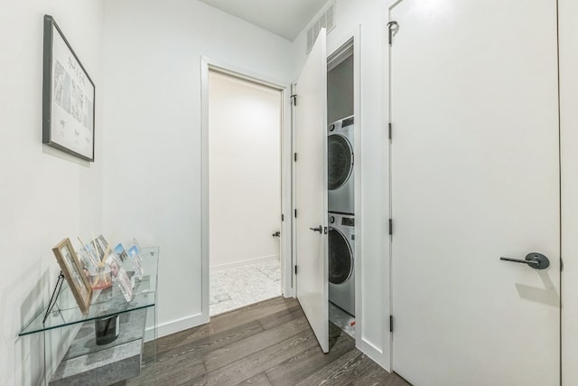 clothes washing area featuring stacked washer / drying machine and dark hardwood / wood-style flooring