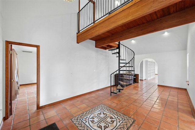 staircase with beam ceiling, high vaulted ceiling, and tile patterned flooring