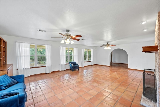 tiled living room with a textured ceiling, a healthy amount of sunlight, and ceiling fan