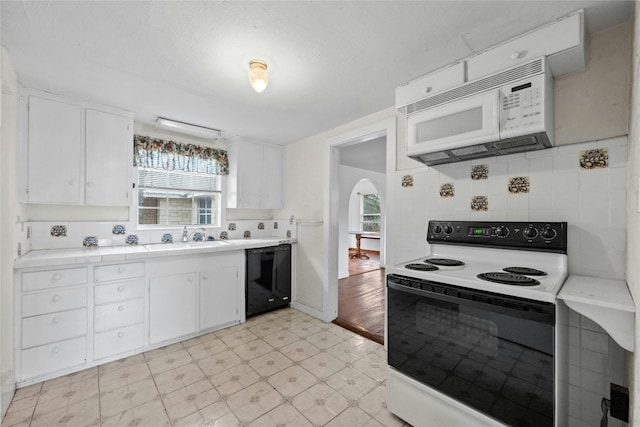 kitchen featuring white appliances, backsplash, white cabinetry, and sink