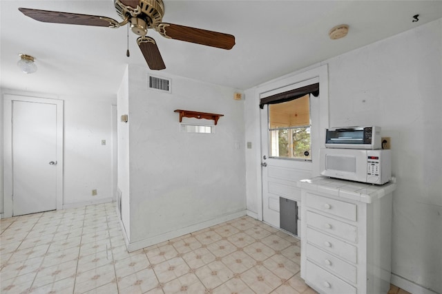 kitchen with tile countertops, white cabinetry, and ceiling fan