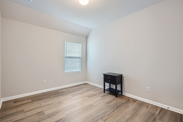 empty room with light wood-type flooring and vaulted ceiling