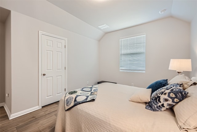 bedroom featuring hardwood / wood-style floors and vaulted ceiling