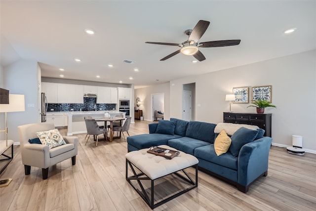 living room featuring ceiling fan, sink, and light hardwood / wood-style flooring