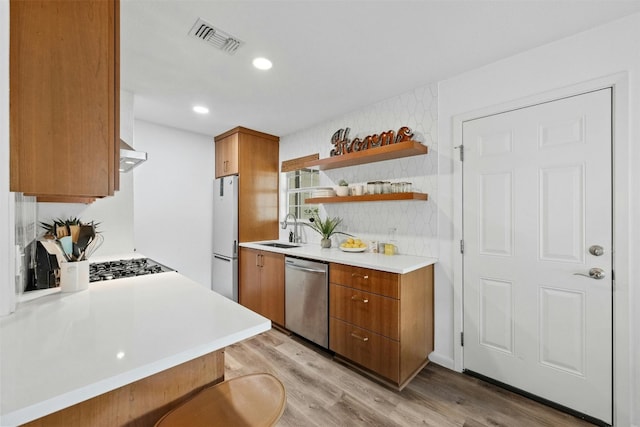 kitchen with kitchen peninsula, stainless steel dishwasher, light hardwood / wood-style floors, sink, and white fridge