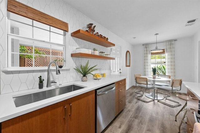 kitchen featuring sink, stainless steel dishwasher, decorative light fixtures, decorative backsplash, and hardwood / wood-style flooring