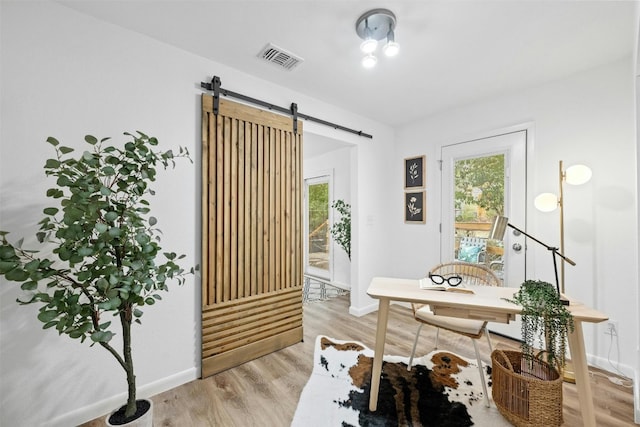 office area with a barn door and light hardwood / wood-style flooring