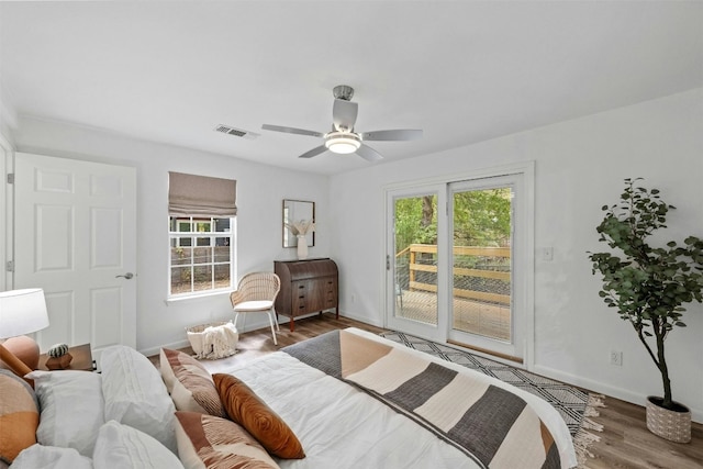 bedroom featuring hardwood / wood-style flooring, ceiling fan, access to exterior, and multiple windows