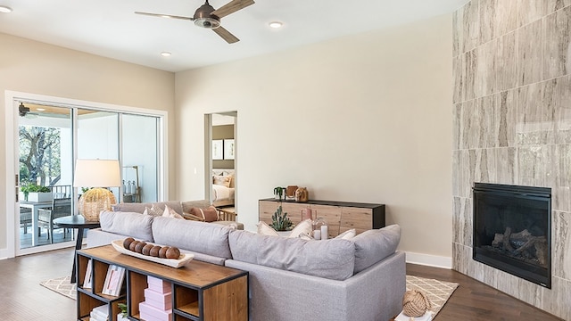 living room featuring ceiling fan, dark hardwood / wood-style flooring, and a tile fireplace