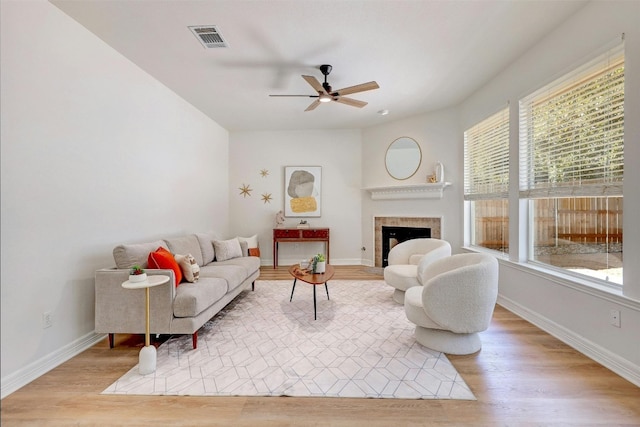 living room with light hardwood / wood-style flooring, a tile fireplace, and plenty of natural light